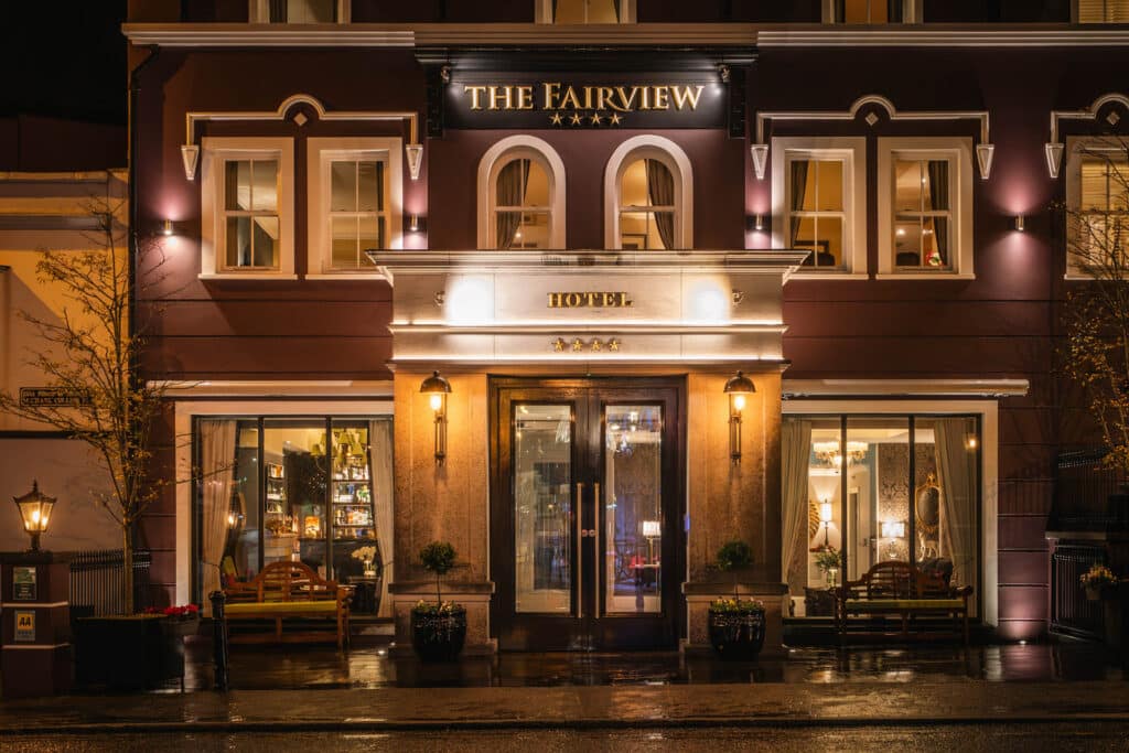 Front entrance of the Fairview Hotel at night with illuminated signage and glass doors.