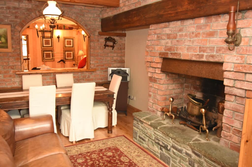 Dining space within the CK Apartment with table seating and exposed brick fireplace.