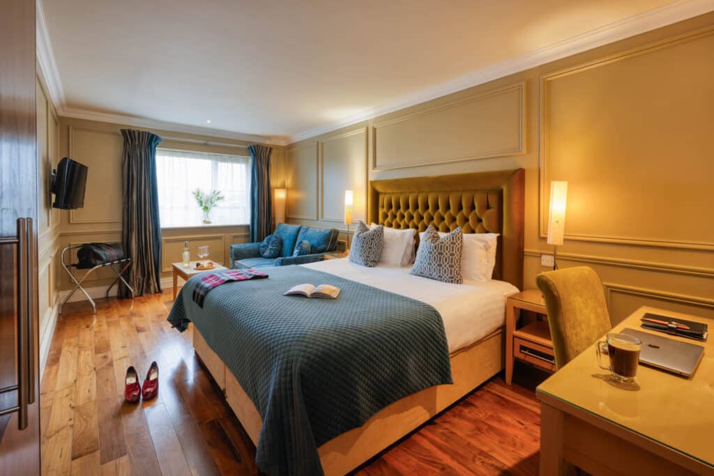 Executive double bedroom with king-size bed, seating area and wooden flooring.