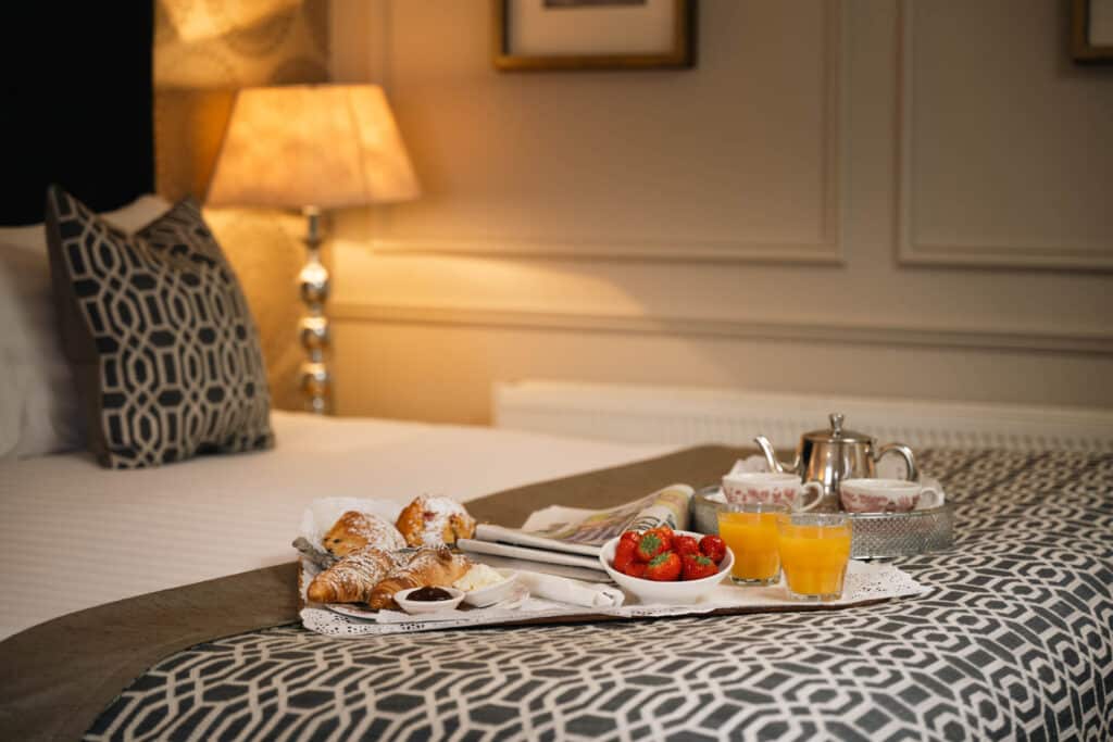 Bed with breakfast tray and soft furnishings.