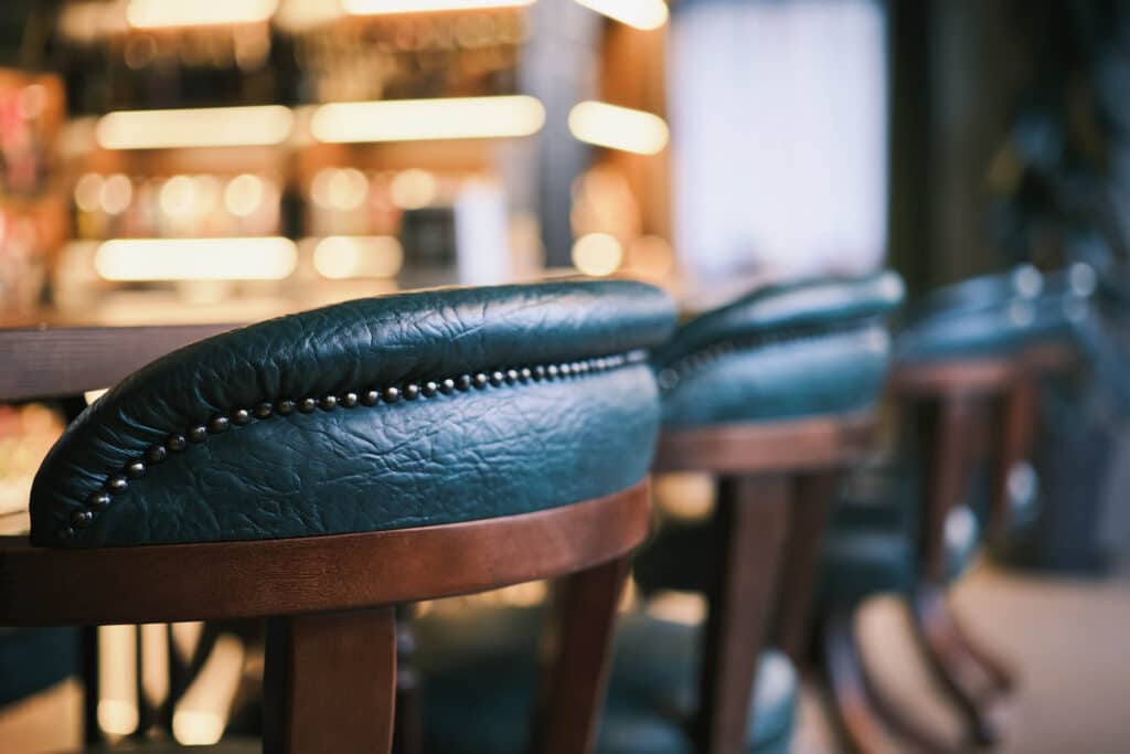 Leather bar stools lined along a bar counter, creating a warm and inviting pub or hotel bar interior.