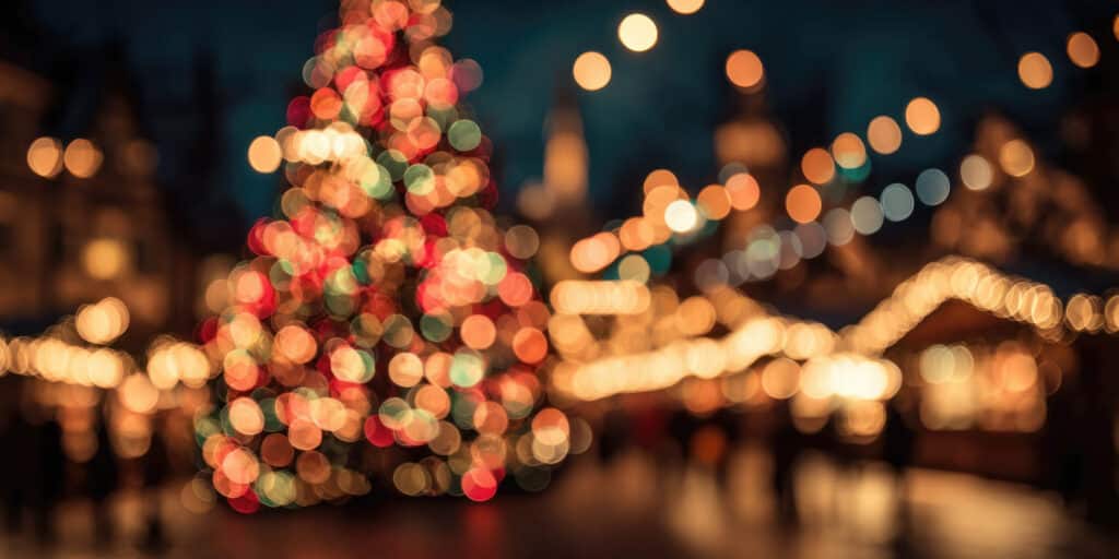 Blurred lights of Christmas market in european city, warm bokeh background of gold and red.