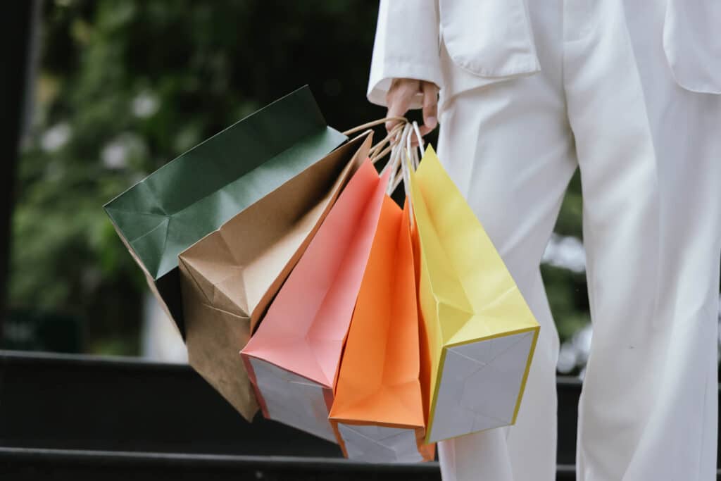 Person carrying colourful shopping bags outdoors, suggesting retail shopping and leisure in a town setting.