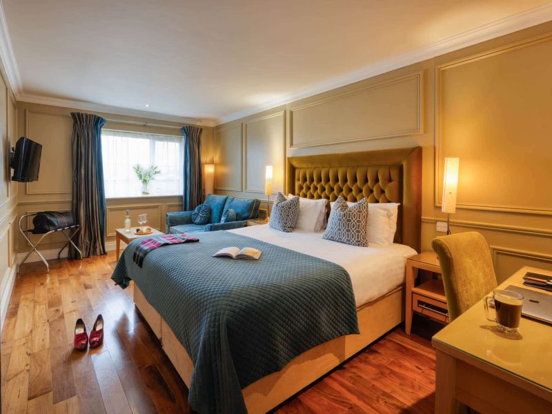 Executive double bedroom with king-size bed, seating area and wooden flooring.